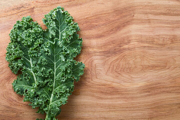 Fresh raw curly kale or leaf cabbage (lat. Brassica oleracea) photographed overhead on wood (Selective Focus) - obrazy, fototapety, plakaty