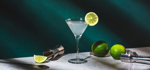 Vodka gimlet alcoholic cocktail drink with vodka, syrup, lime juice and ice, dark green background,...