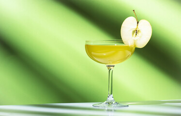 Apple pie alcoholic cocktail beverage with vodka, apple liqueur, cinnamon syrup.. Light green background, hard light, shadow pattern. Minimalistic style