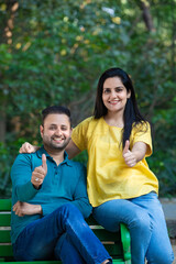 Naklejka premium Happy young indian man and woman showing thumps up at park.
