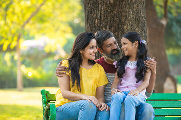 Happy indian couple with his little girl at garden.