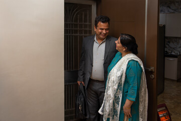 Woman saying goodbye to her husband at the door while going to office