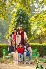 Fototapeta na wymiar happy Indian family sitting at park in winter wear or warm clothes.
