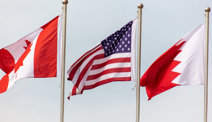 USA flag of Canada and Qatar on sky background.