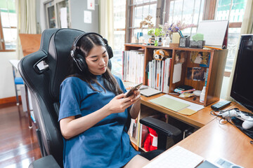 Portrait of beautiful young adult asian gamer woman hand sitting on gaming chair wear headset © dodotone
