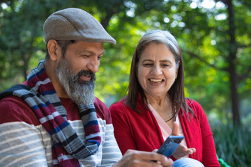 Indian old couple using smartphone at park