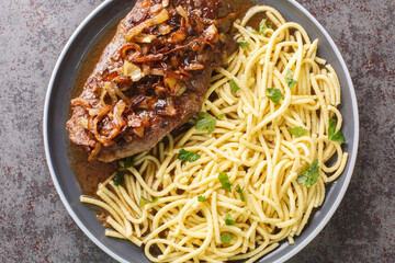 Zwiebelrostbraten onion topped roast beef with gravy and spaetzle closeup on the plate on the table. Horizontal top view from above
