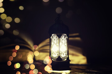 Ramadan Kareem background. Ornamental Arabic lantern glowing and the holy book of Quran.