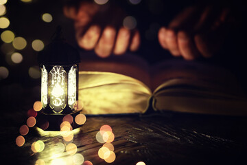Ramadan Kareem background. Ornamental Arabic lantern glowing and the holy book of Quran.