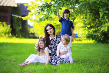 Obraz premium Young large family on a summer morning walk. Beautiful mother with children is playing in the park.