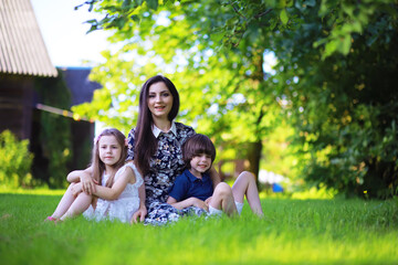 Obraz premium Young large family on a summer morning walk. Beautiful mother with children is playing in the park.