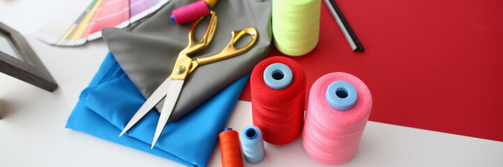 Multicolored fabric threads and scissors in atelier at workplace