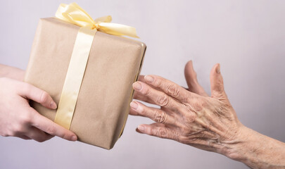 Hands of an old elderly woman receiving a gift from a girl. Close-up.