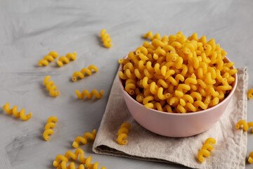 Homemade Organic Dried Riccioli Pasta in a Pink Bowl, low angle view.
