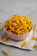 Homemade Organic Dried Riccioli Pasta in a Pink Bowl, side view.