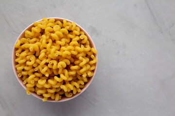 Homemade Organic Dried Riccioli Pasta in a Pink Bowl, top view. Flat lay, overhead, from above. Copy space.