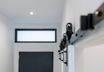 Black sliding door wheels on a white wooden door