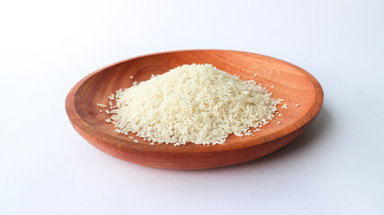 Close up photo rice on wooden plate isolated on white background. Slanted angle.