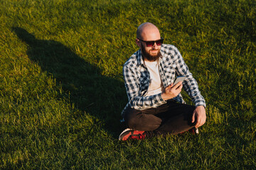 Naklejka na ściany i meble A young man sits on the green grass.