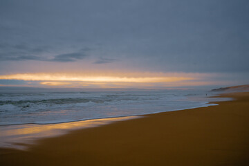 Fototapeta na wymiar Dramatic sunset on the beach. Wide sandy beach, stormy sea, and beautiful cloudy sky