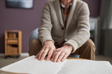 Senior man with disability reading a book in Braille
