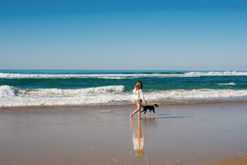 Young woman walking and playing on the Oceanic beaches of Aquitaine with their puppies