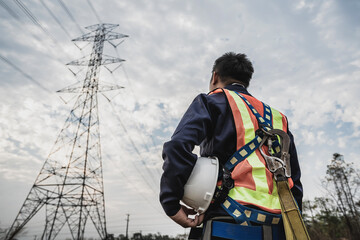 Asian electrical engineer wearing safety gear working high voltage pylon Engineering work on...