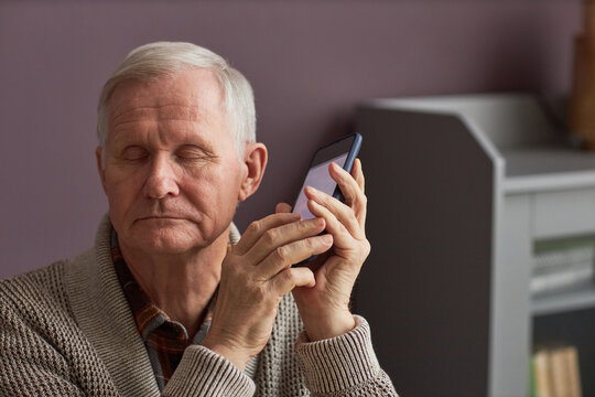 Senior man with blindness listening to audio assistant