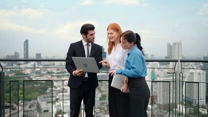 A team of business people standing and disscuss using laptop to work at rooftop city view