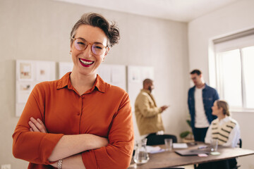 Cheerful businesswoman smiling at the camera while standing in an office