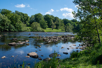 A sunny summer's day, with blue skies over River North Tyne at Chesters in Northumberland, UK