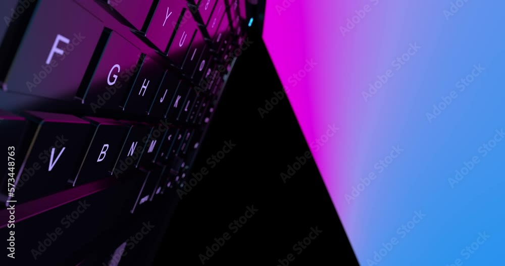 Poster 4k resolution video: сamera аlies between the glowing keyboard and the laptop screen extreme closeup