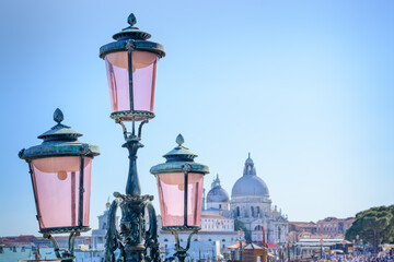 Top of street lamp with pink glass of Saint Mark's square on blurred background