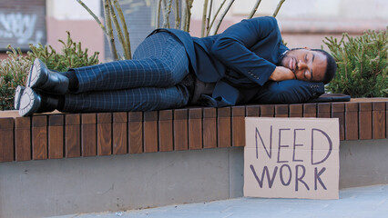 Sleeping homeless fired African American man in city tired with searching job relax on bench. Male...