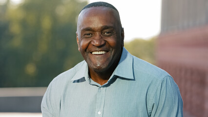 Close up male happy smiling toothy face. Portrait in city outdoors African American mature senior...