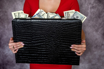 Businesswoman wear red dress holding case full of dollar money