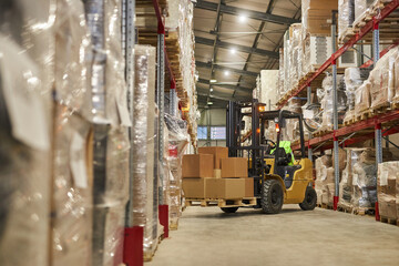 Obraz na płótnie Canvas Background image of warehouse interior with forklift carrying boxes, copy space