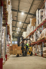 Vertical background image of warehouse interior with forklift carrying boxes
