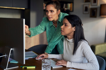Freelancer discussing over computer with colleague at home office