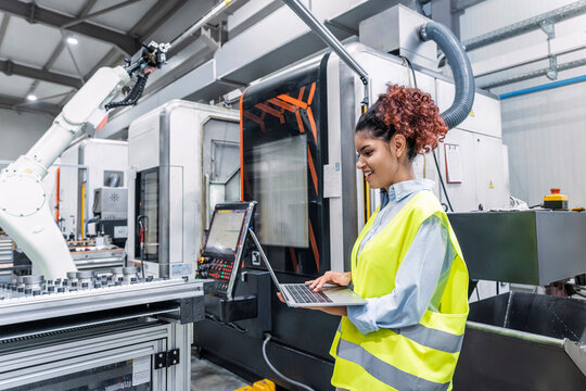 Happy engineer using laptop in factory