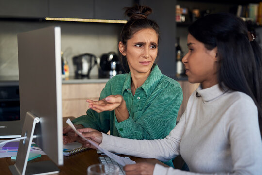 Freelancers discussing over document at desk in home office