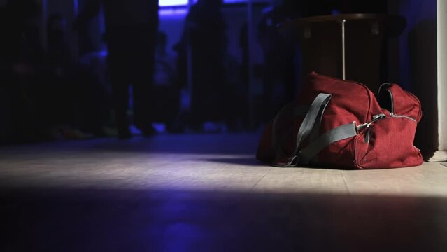 Red Sports Bag Is On Floor In Dark Locker Room Before Start Of Football Match. Team Players Change Into Soccer Uniforms In Dressing Room. Cloakroom