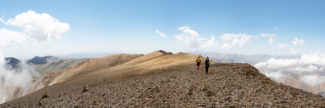 Friends mountaineering amidst cloudy sky on weekend