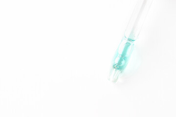 Dropper pipette with blue liquid gel, acid, serum on white isolated background