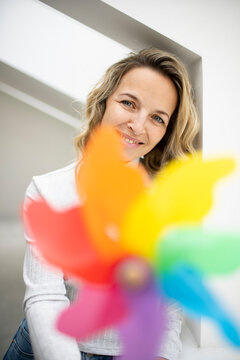 Smiling mature woman behind colorful pinwheel toy