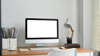 Blank computer screen, lamp and supplies on wooden desk. Empty screen for your advertising and creative design