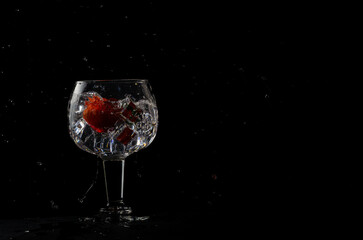 glass of gin and tonic with strawberry on a black background