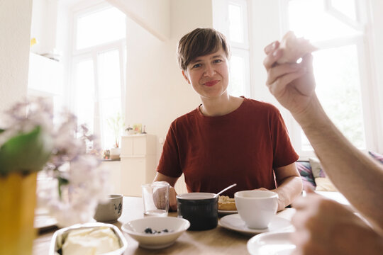 Smiling woman with breakfast on table at home