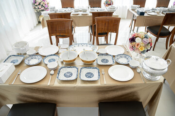 Elegant white ceramic crockery, expertly placed on the table, sets the stage for a memorable meal.