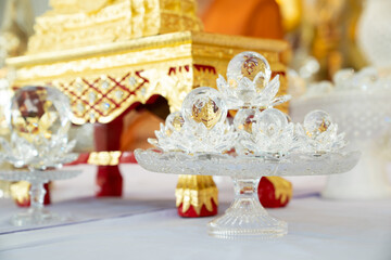 A crystal ball, its surface reflecting the light, sits atop a pile of fragile crystal flower petals in a Thailand temple, adding an air of mystery to the sacred space.